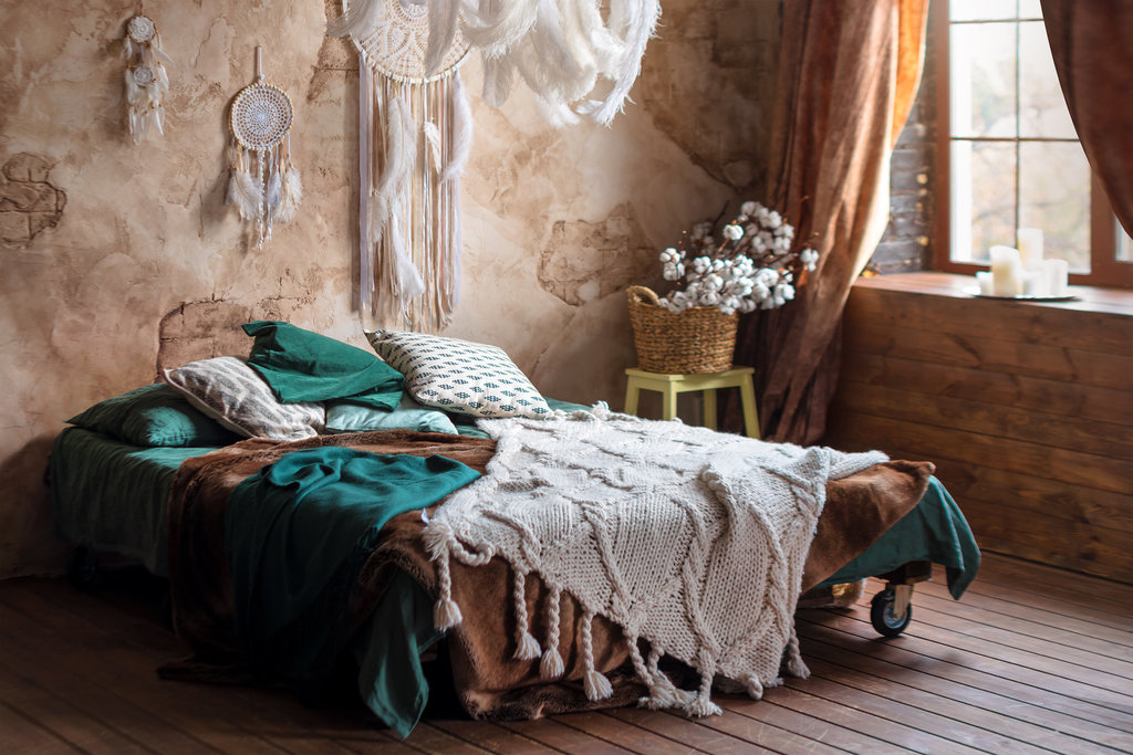 slaapkamer in hout- en natuurstijl met een dromenvanger boven het bed.