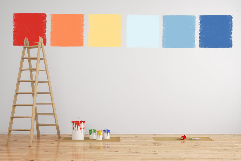 neutrale muur waarop verschillende vierkanten verfkleuren zijn geschilderd. op de vloer staan een ladder en verfpotten en een kwast.